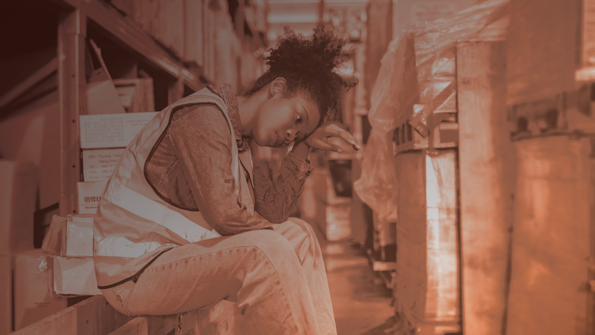 Woman worker sitting down in a warehouse looking hot and stressed.