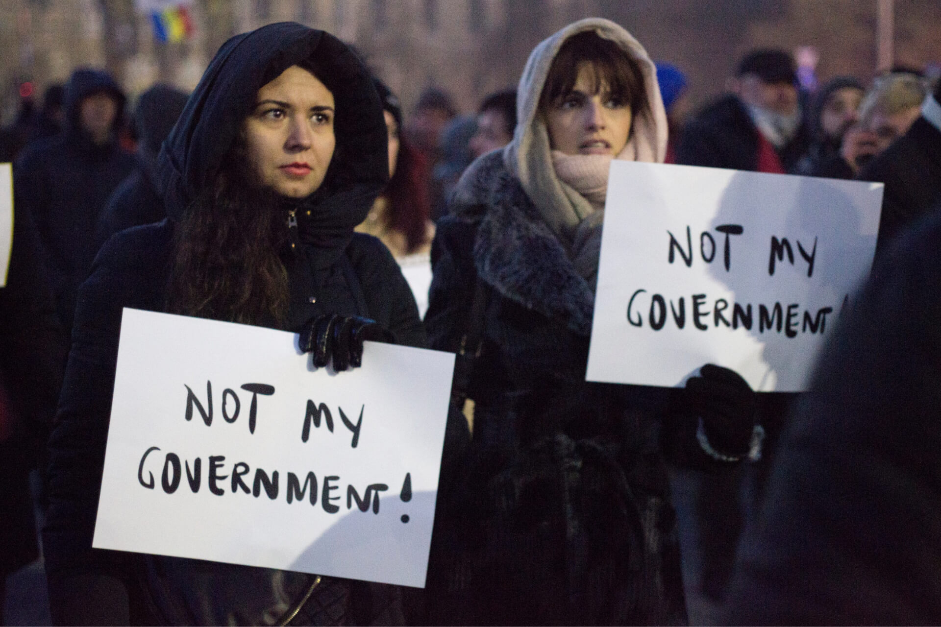 Women holding signs that read, "Not my government"